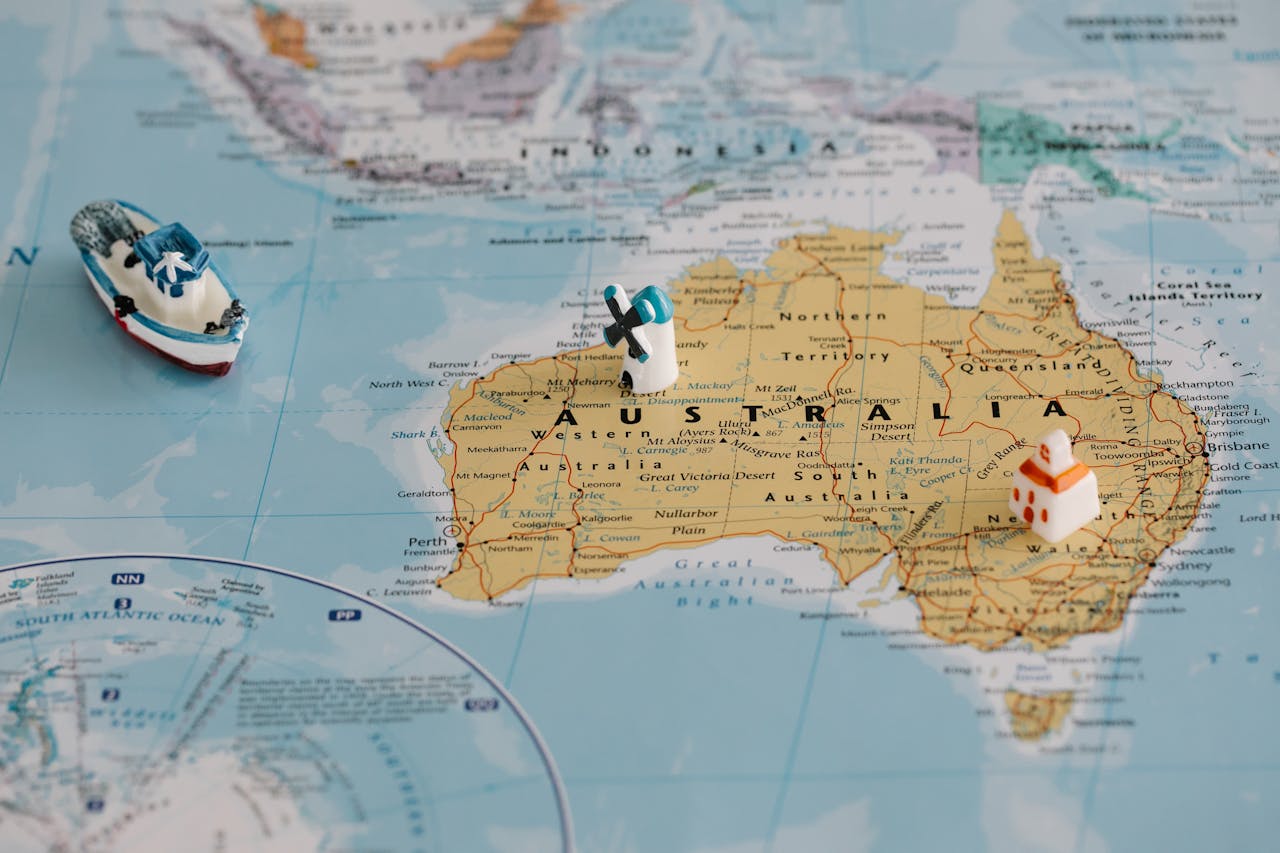 Miniature windmill and ship placed atop a map of Australia, highlighting travel concepts.
